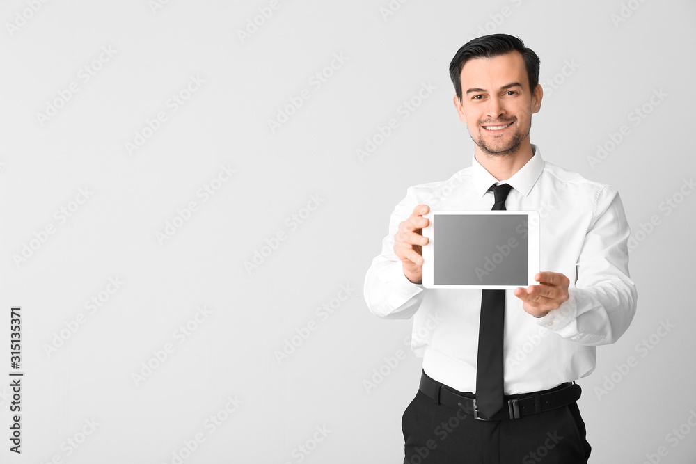 Male real estate agent with tablet computer on light background Male real estate agent with tablet computer on light background