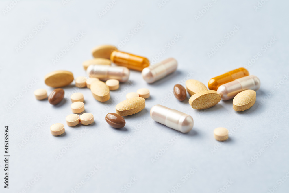 Multicolor vitamins and supplements on bright paper background. Concept for a healthy dietary supplementation. Close up. 