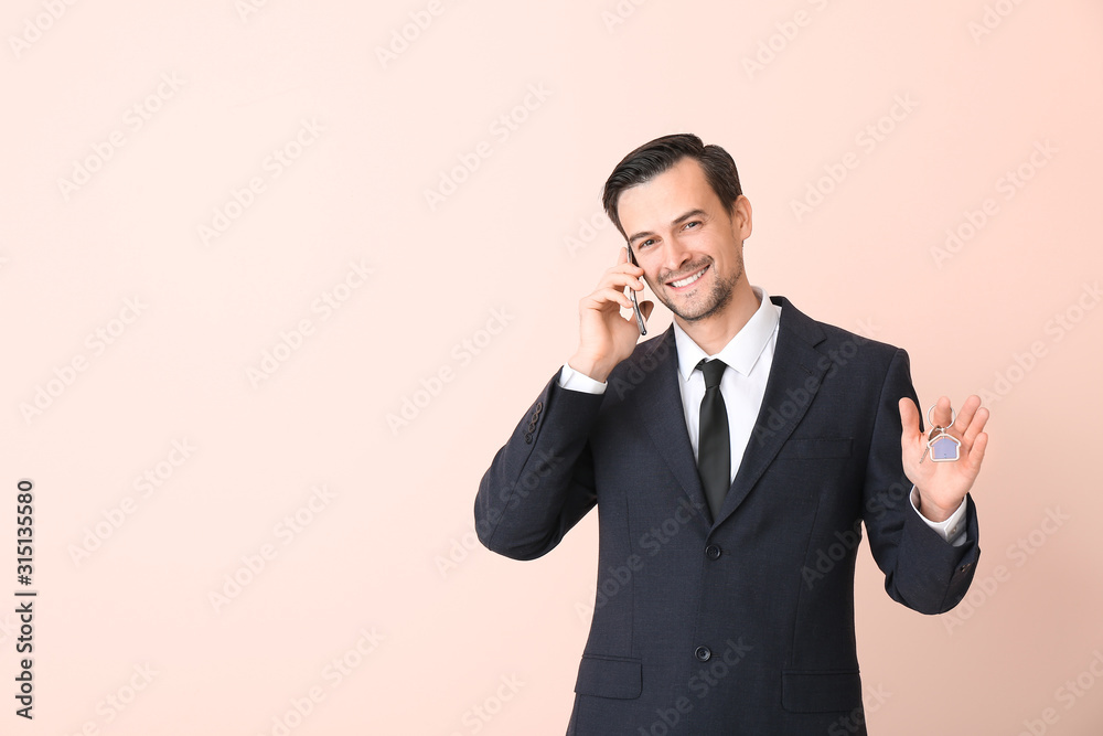 Male real estate agent with key talking by mobile phone on color background Male real estate agent with key talking by mobile phone on color background
