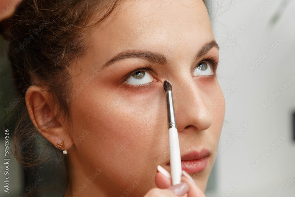 The process of creating makeup. Makeup artist working with a brush on the face of the model. The process of creating makeup. Makeup artist working with a brush on the face of the model.