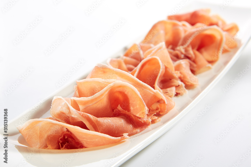 Sliced Jamon Iberico, Prosciutto or Speck on Restaurant Plate Isolated Sliced Jamon Iberico, Prosciutto or Speck on Restaurant Plate Isolated