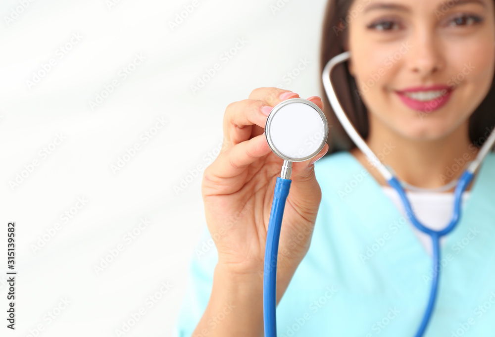 Female cardiologist with stethoscope on light background, closeup Female cardiologist with stethoscope on light background, closeup
