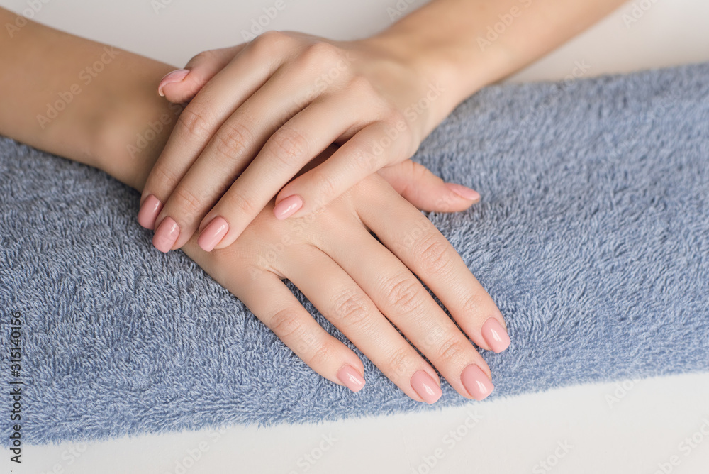 Preparation for manicure. The hands of a young girl lie on a classic blue towel on the table. Nude manicure. Hand care