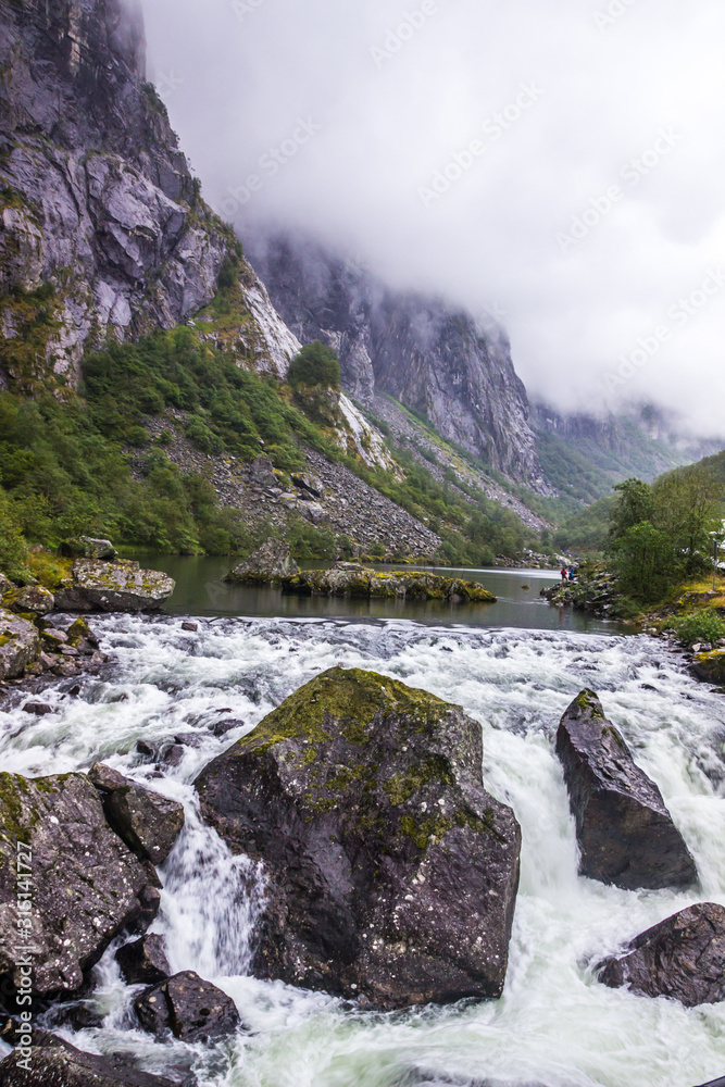 rocks in a rushing mountain river during a rainy day in Norway
