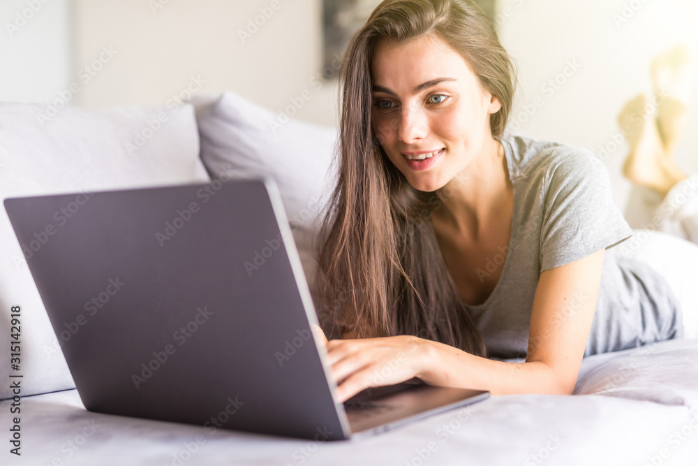 Young woman using a laptop while relaxing on the couch Young woman using a laptop while relaxing on the couch