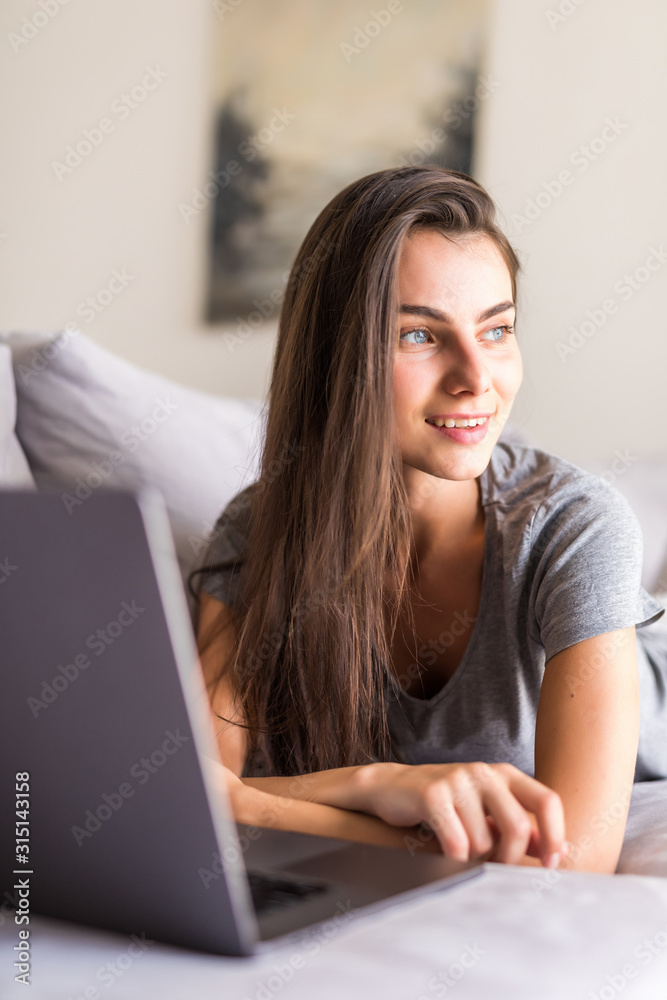 Young woman using a laptop while relaxing on the couch Young woman using a laptop while relaxing on the couch