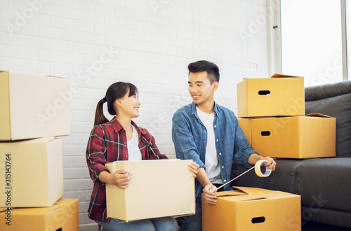 Canvas Print Young couple Asian man and woman Packing boxes and carrying large packed carton cardboard boxes on moving day at new home  luxury house or apartment