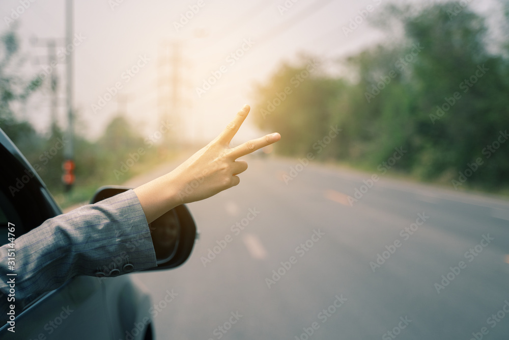 Freedom  independence liberty  concept, women hand giving two fingers up sign throw the window of a car parked near the roads show a symbol of a hand raised for good signal.when the car is broken