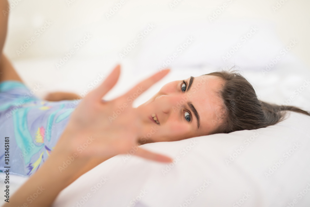 Young pretty woman lying in underwear in white bed and cover camera with hands Young pretty woman lying in underwear in white bed and cover camera with hands
