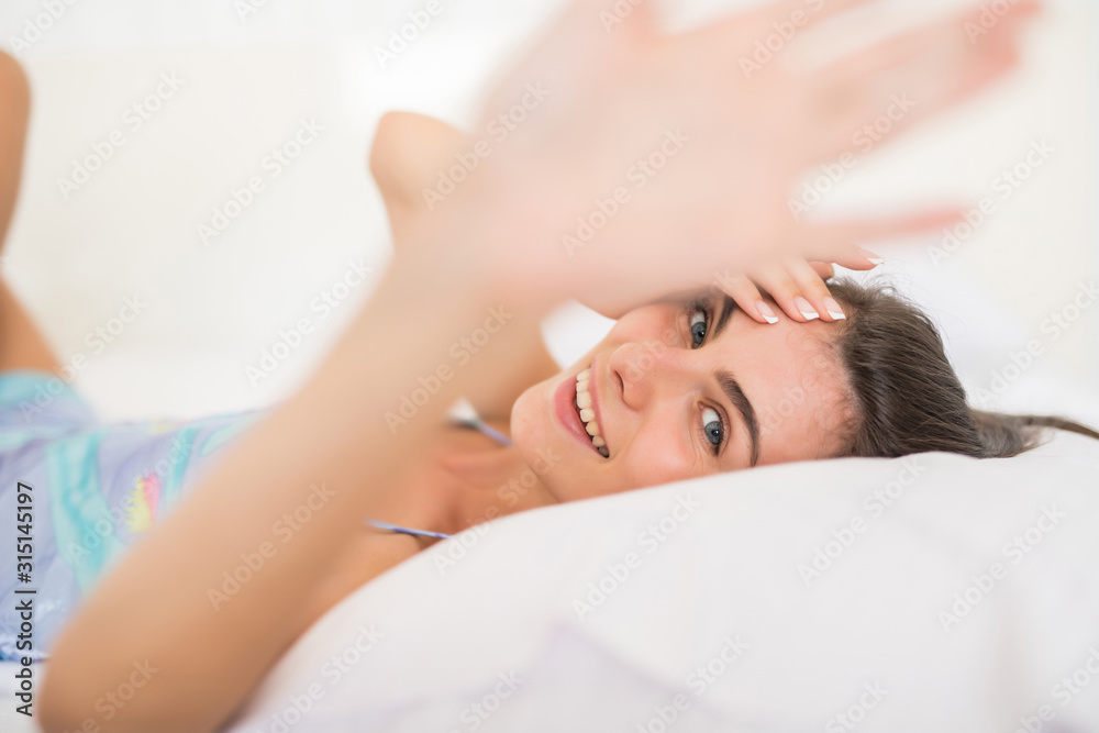 Young pretty woman lying in underwear in white bed and cover camera with hands Young pretty woman lying in underwear in white bed and cover camera with hands