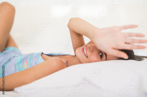 Pretty young woman lying down on her bed at home