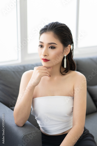 Free Download happy young Asian business woman  smiling and sittng on sofa. Looking camera , she is very excited - GFXLoad