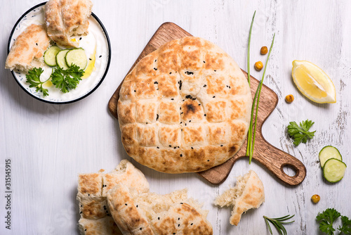 Flatbread, baked traditional oriental or indian bread with yoghurt dip photo