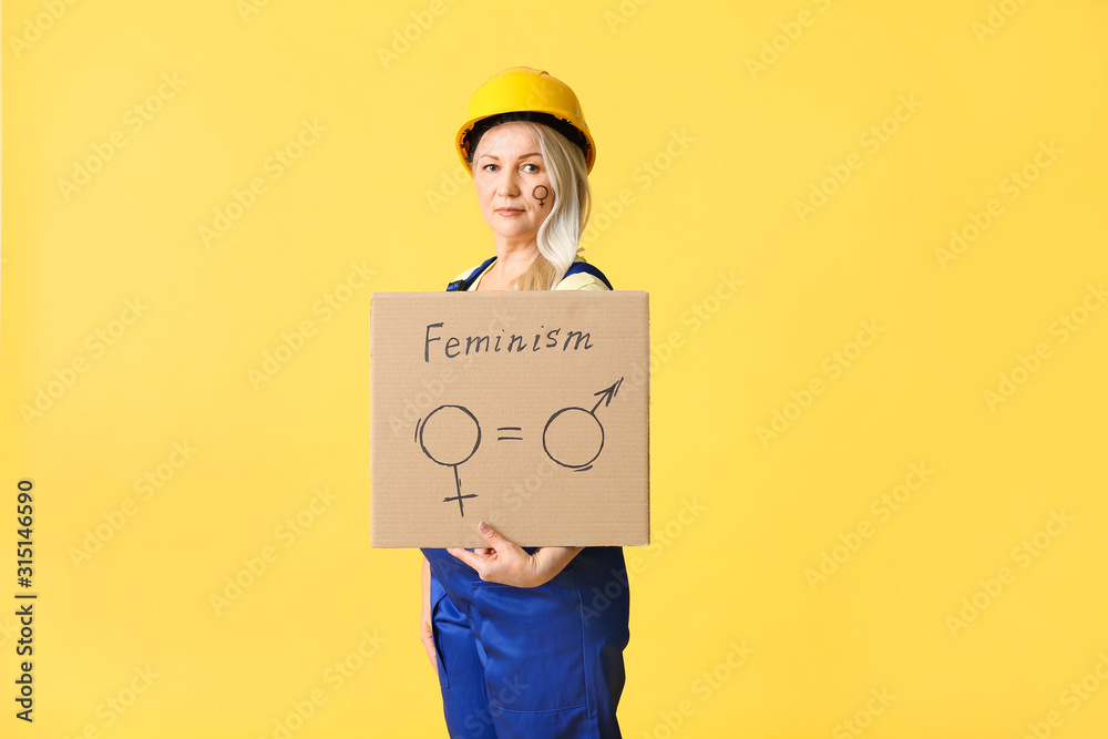 Worker holding cardboard with symbols of man and woman on color background. Concept of feminism Worker holding cardboard with symbols of man and woman on color background. Concept of feminism