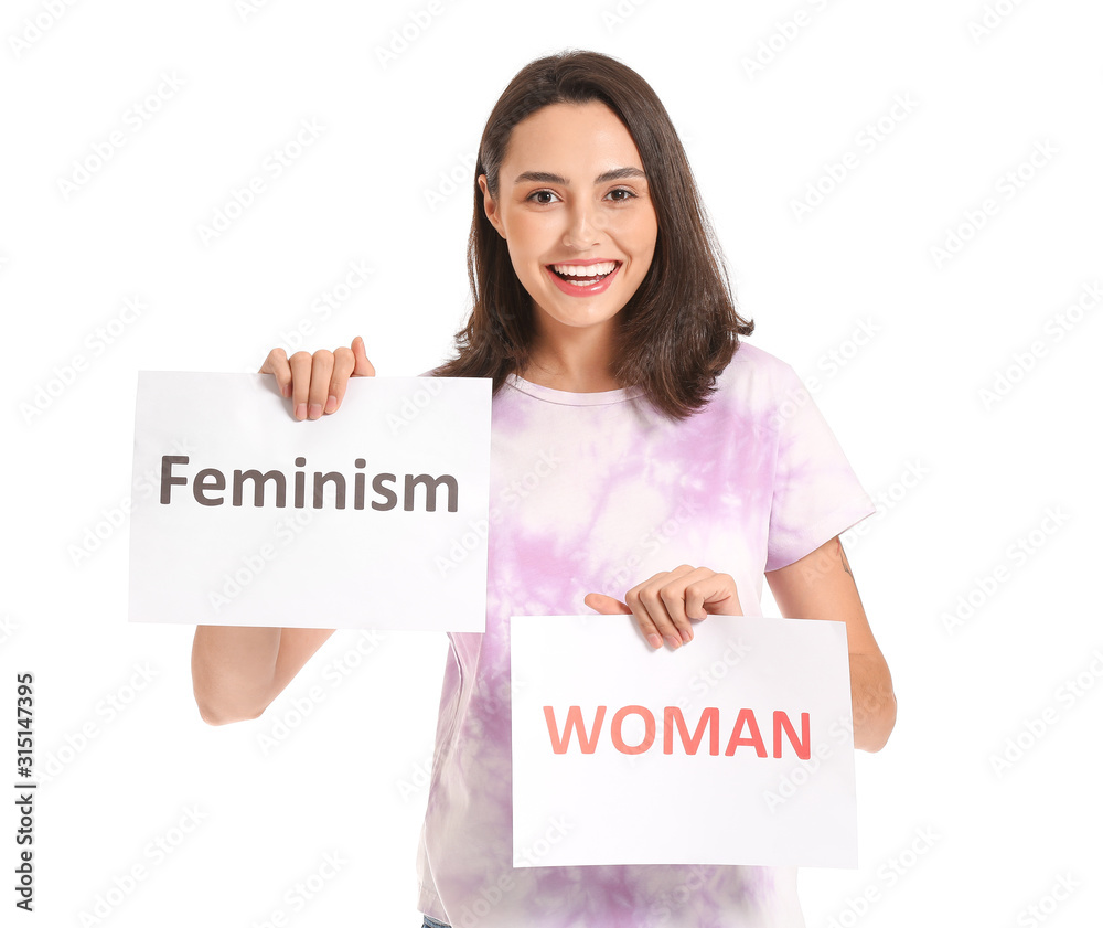 Young lady holding papers with text WOMAN and FEMINISM on white background Young lady holding papers with text WOMAN and FEMINISM on white background