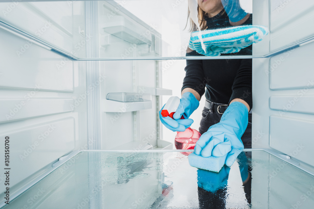 Φωτογραφία Cropped view of woman in rubber gloves cleaning refrigerator with detergent isol