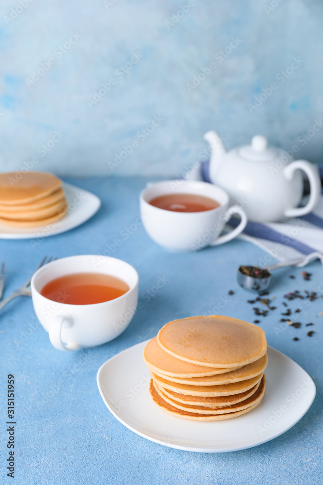 Plate with tasty pancakes and tea on table