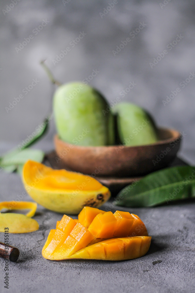 Photo of fresh green mango in a bowl. Mango slice with green leaves. Healthy breakfast. Tropical fruit. Summer. Still life photography. Image