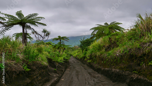 Dark rainstorm clouds gather above the turquoise colored ocean and muddy trail.