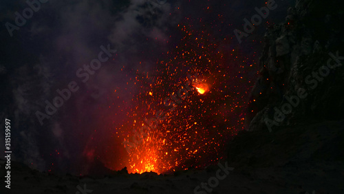 CLOSE UP: Glowing pieces of lava fly up in the air out of an active volcano. © helivideo
