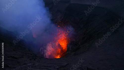 CLOSE UP: Bright orange pieces of magma are blasted out of an active volcano.