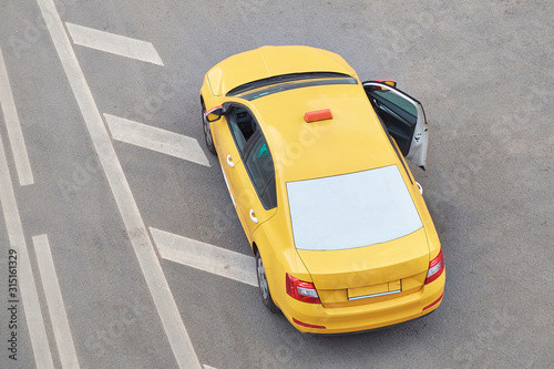 Yellow taxi car on the pavement with an open door, top view