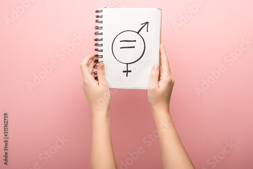 cropped view of woman holding notebook with male and female sign on pink background