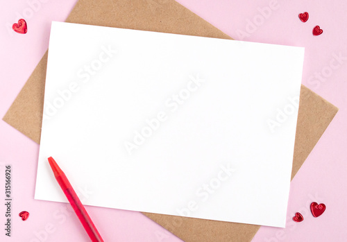 Minimalistic card mockup with envelope, postcard, pen, red hearts on pink background. Flat lay, top view, copy space. Valentines day, birthday concept.
