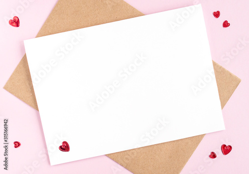 Minimalistic card mockup with envelope, postcard, red hearts on pink background. Flat lay, top view, copy space. Valentines day concept.