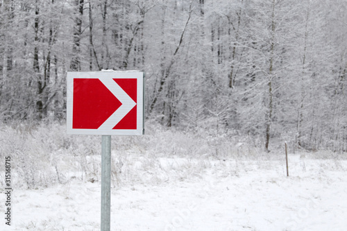 Traffic sign of turn on a winter road in a snow-covered forest. Turn signal in the countryside