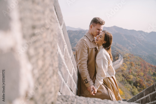 beautiful young couple showing affection on the Great Wall of China. Newly married couple on their honemoon to Great Wall near Beijing China. Stylish couple exploring one of the wonders of the world photo