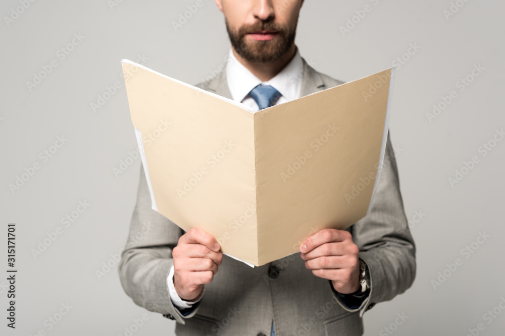 partial view of businessman holding paper folder isolated on grey partial view of businessman holding paper folder isolated on grey