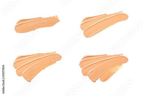 Bright beige smear of foundation in the form of a group of diagonal strokes isolated on a white background.