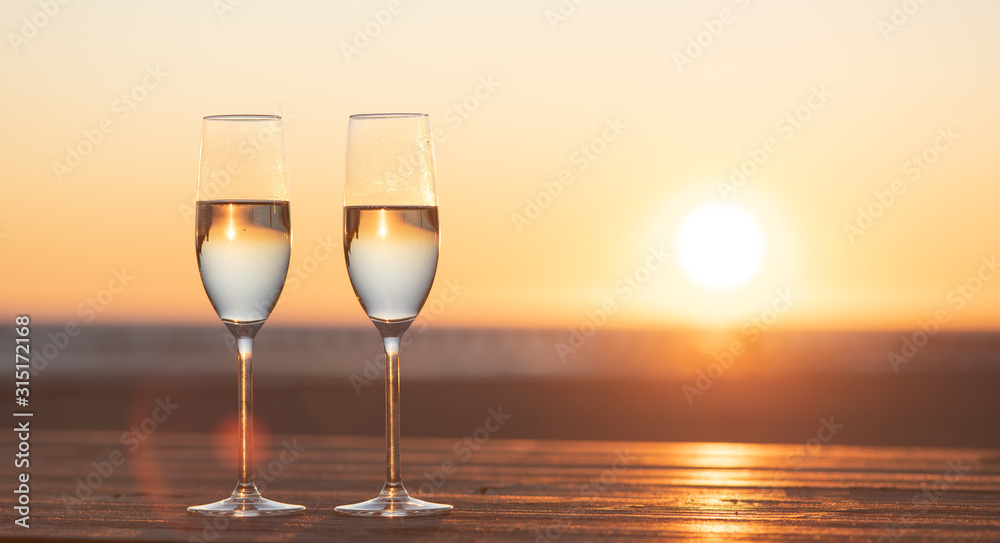 two glasses of champagne on the table at sunset