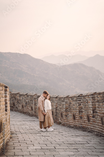 beautiful young couple showing affection on the Great Wall of China. Newly married couple on their honemoon to Great Wall near Beijing China. Stylish couple exploring one of the wonders of the world photo