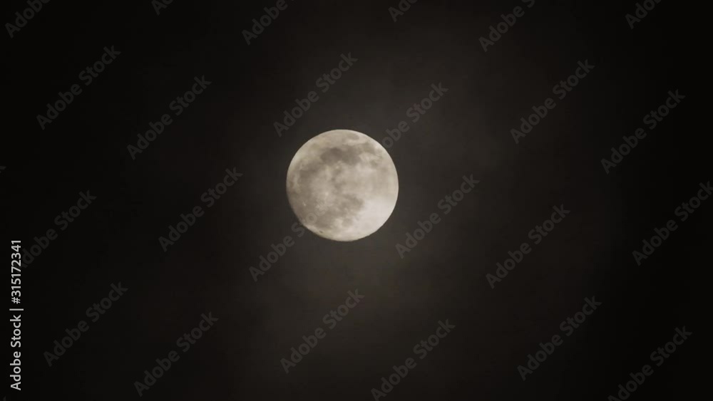 Full moon on dark cloudy night. Clouds passing by the moon, real time shot. Full moon on dark cloudy night. Clouds passing by the moon, real time shot.