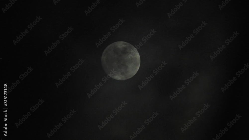 Full moon on dark cloudy night. Clouds passing by the moon, real time shot. Full moon on dark cloudy night. Clouds passing by the moon, real time shot.