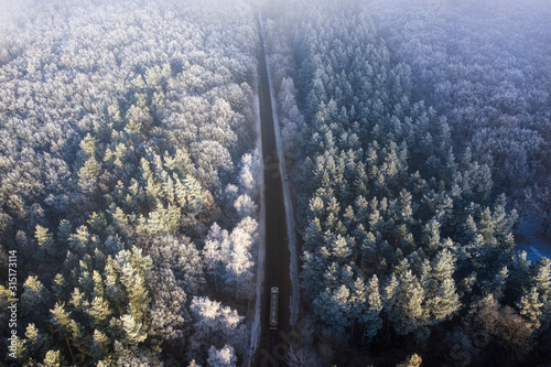 Aerial view of the drone for the road in the winter coniferous forest.