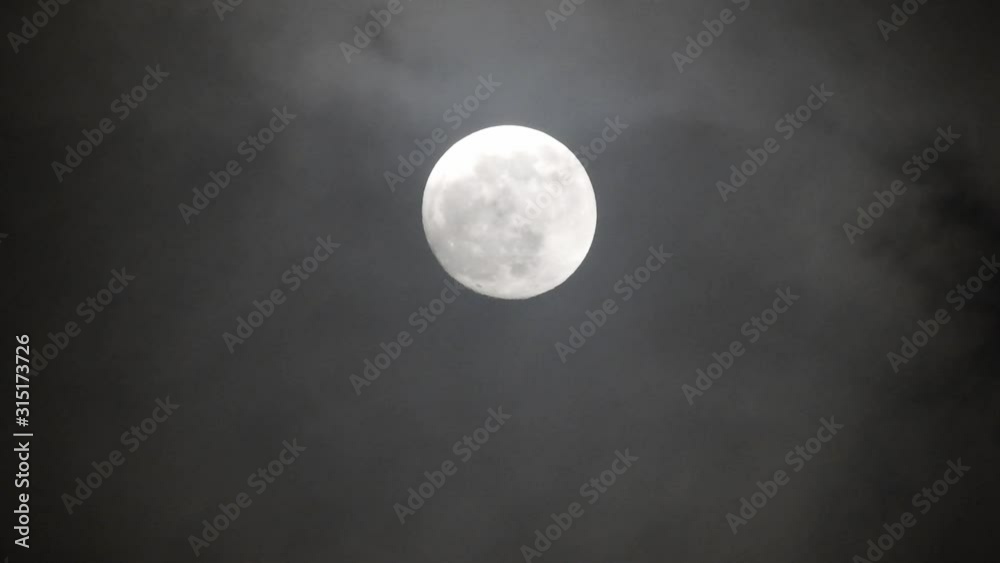 Full moon on dark cloudy night. Clouds passing by the moon, real time shot. Full moon on dark cloudy night. Clouds passing by the moon, real time shot.