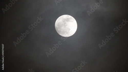 Full moon on dark cloudy night. Clouds passing by the moon, real time shot.