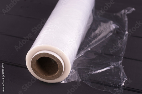 Fotografija Roll of cling film on a black wooden table.