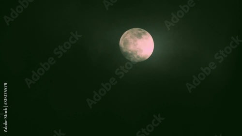 Full moon on dark cloudy night. Clouds passing by the moon, real time shot.