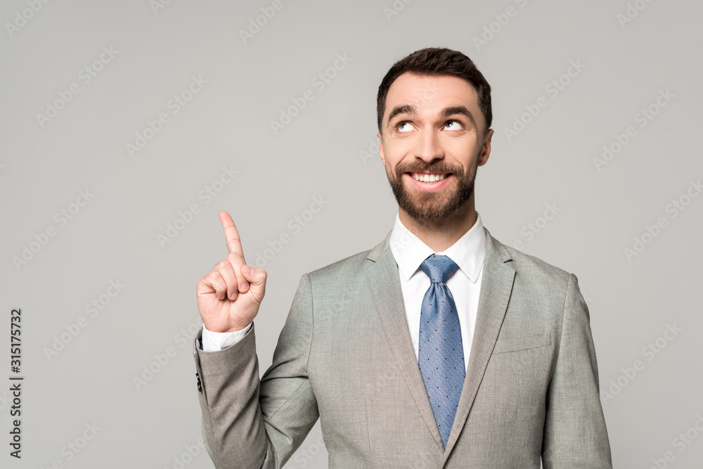 cheerful businessman looking away while showing idea gesture isolated on grey cheerful businessman looking away while showing idea gesture isolated on grey