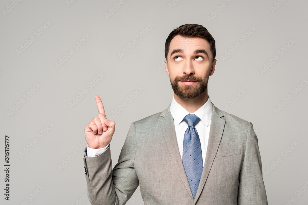 smiling businessman looking away while showing idea gesture isolated on grey smiling businessman looking away while showing idea gesture isolated on grey