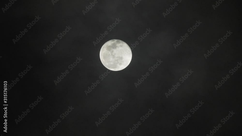 Full moon on dark cloudy night. Clouds passing by the moon, real time shot. Full moon on dark cloudy night. Clouds passing by the moon, real time shot.