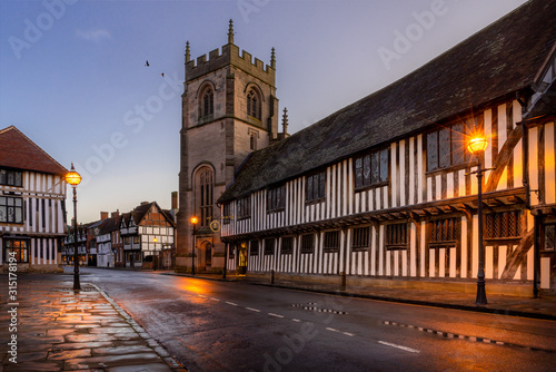 Stratford upon Avon, Guildhall and chapel with church. Street lights shine on timber framed buildings photo