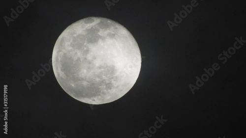 Full moon on dark cloudy night. Clouds passing by the moon, real time shot.