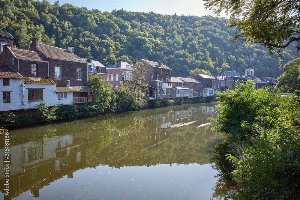 Old red brick houses along the river surrounded by greenery in Chaudfontaine, Belgium