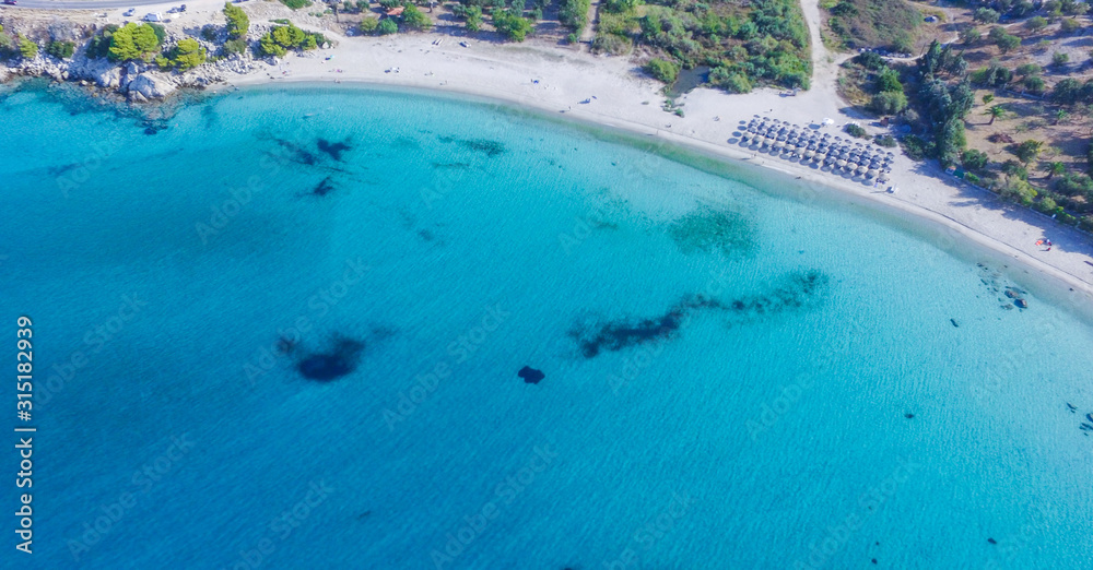 Crystal clear and turquoise sea and white sandy beach surrounded with trees. Aerial view 
