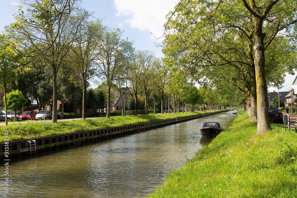 The canal of The Leidsche Rijn in De Meern, near Utrecht The Netherlands on a sunny spring day with trees and boat The canal of The Leidsche Rijn in De Meern, near Utrecht The Netherlands on a sunny spring day with trees and boat